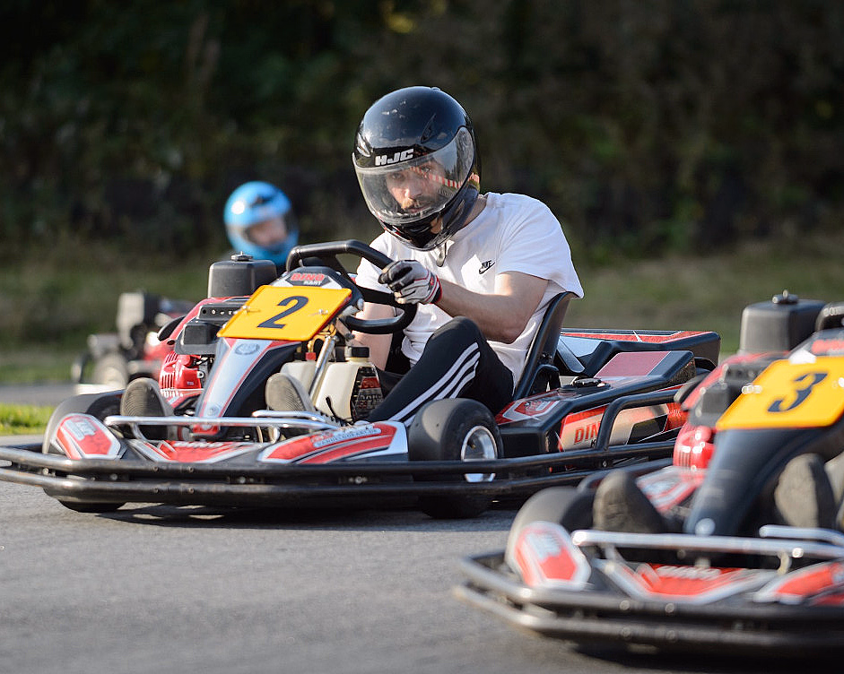 Person med hjelm kjører en rød gokart med nummer 2 på en bane