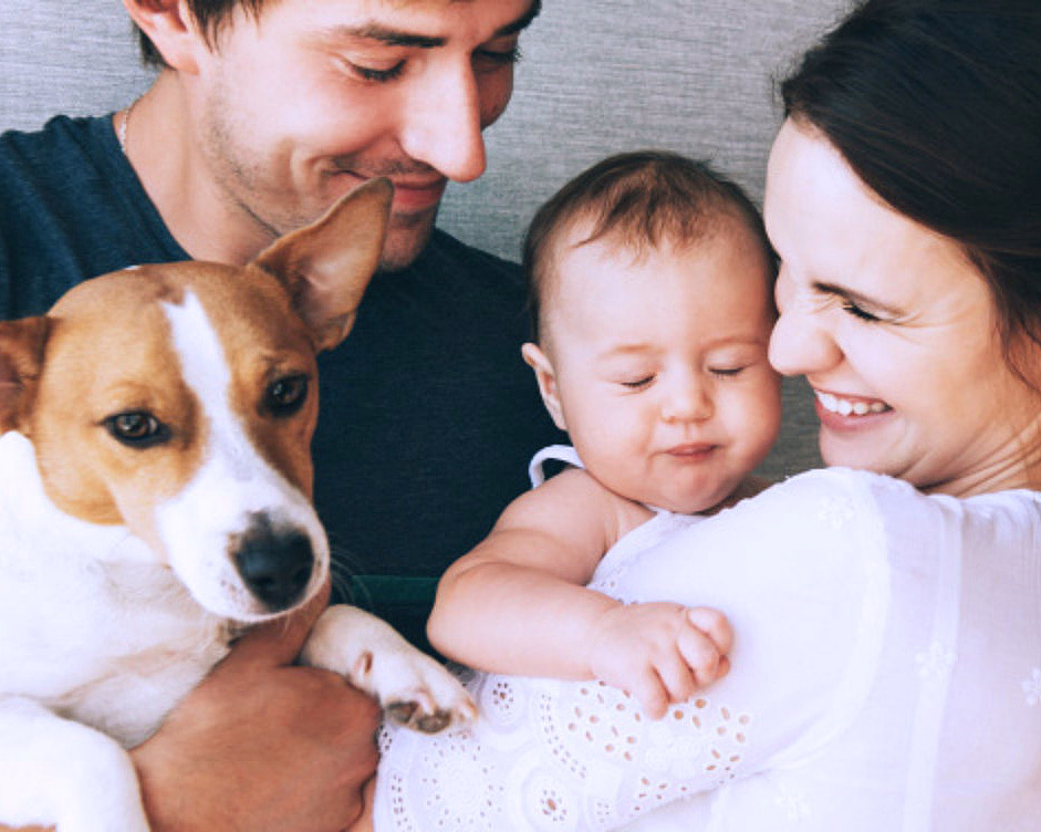 Mann med liten hund og kvinne som holder en baby