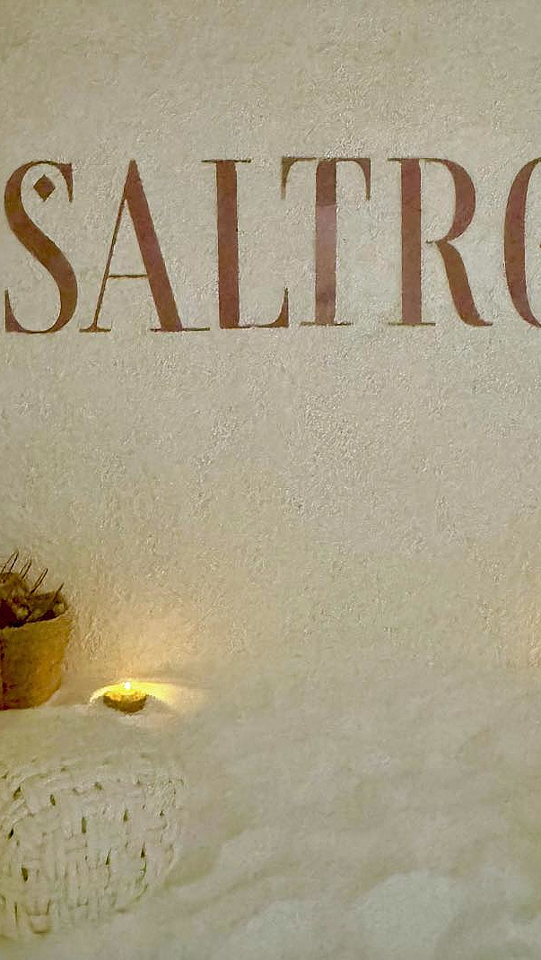 Saltrom med teksten SALTROM på veggen, salt på gulvet, flettede puffer og varm belysning
