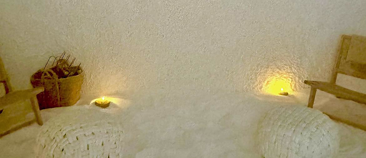 Saltrom med teksten SALTROM på veggen, salt på gulvet, flettede puffer og varm belysning