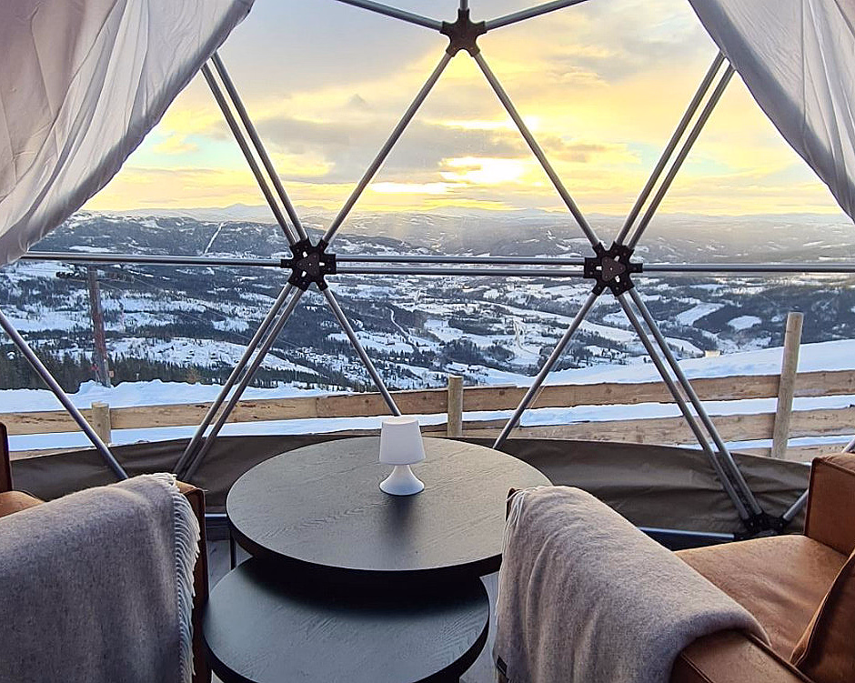 To brune sofaer i en kuppel med store vinduer og utsikt mot snødekte fjell