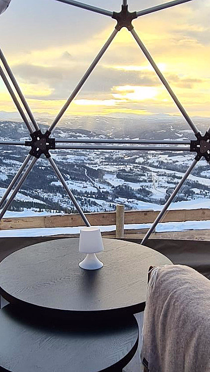 To brune sofaer i en kuppel med store vinduer og utsikt mot snødekte fjell
