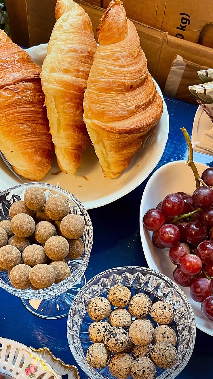 Croissanter, røde druer og konfekt på et blått bord med teksten #eatandpaint