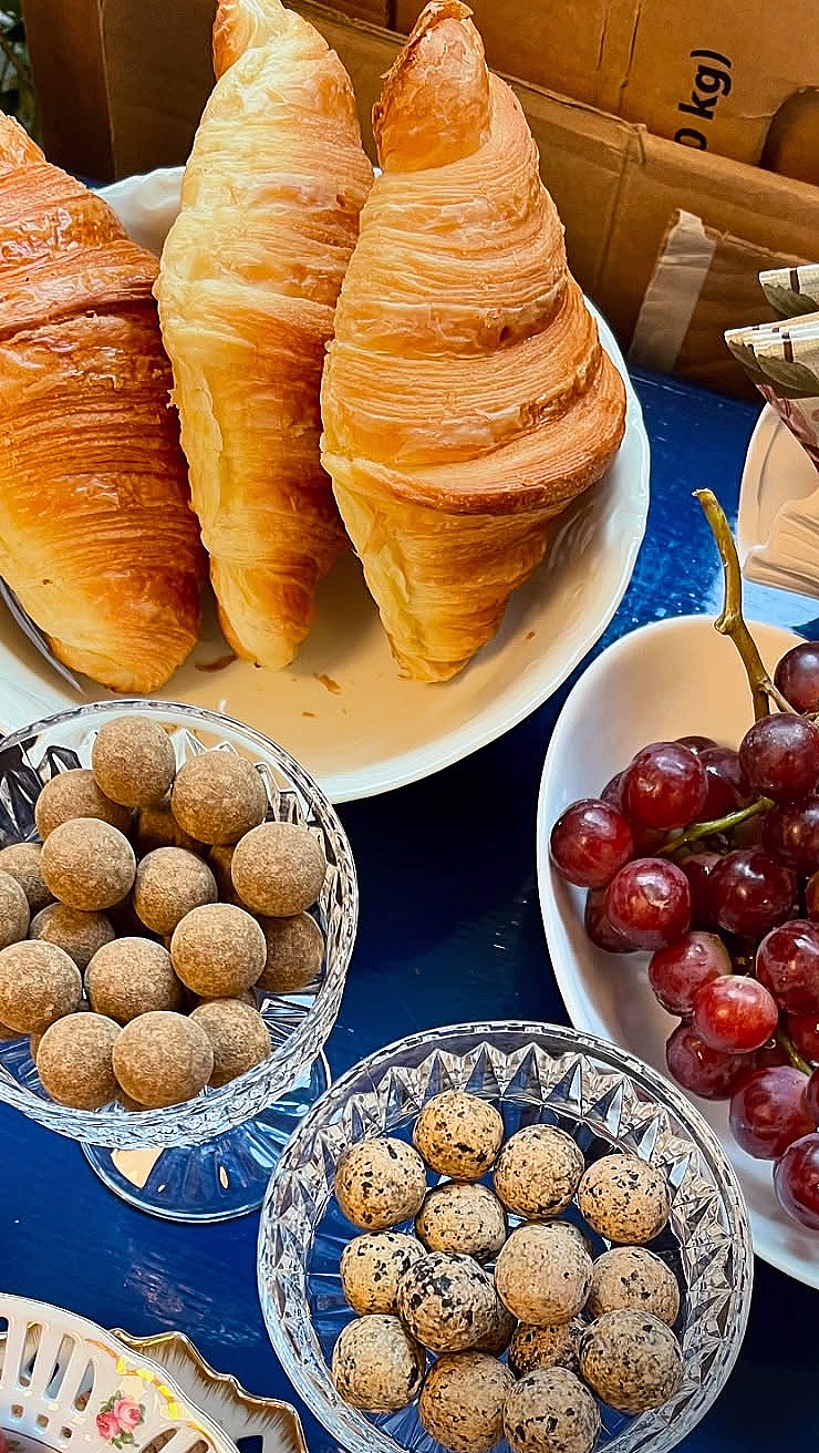 Croissanter, røde druer og konfekt på et blått bord med teksten #eatandpaint