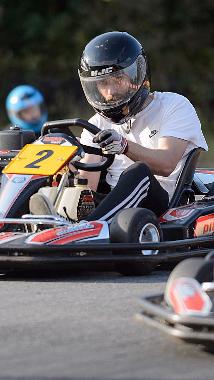 Mann med hjelm kjører gokart på en bane