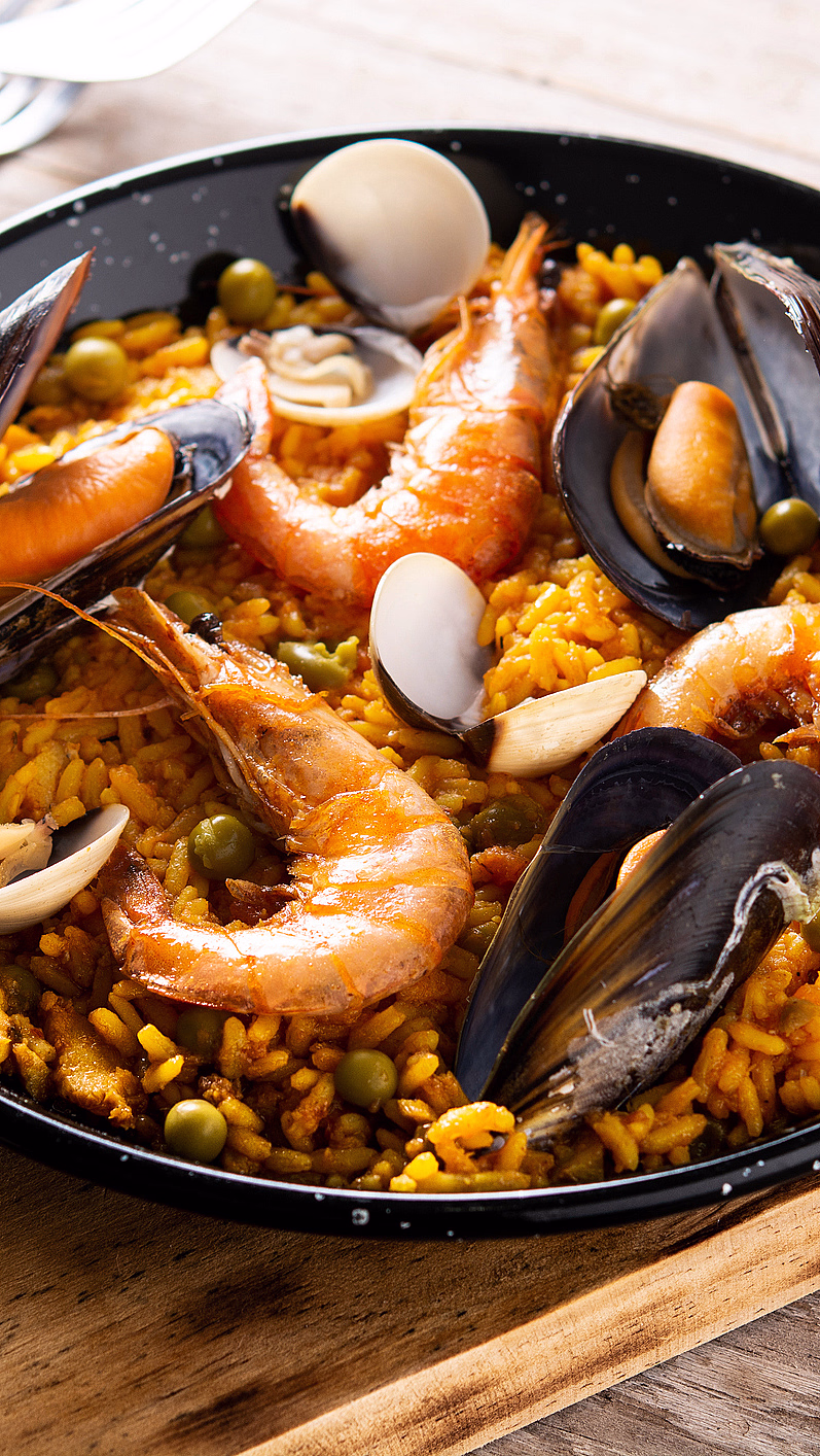 Paella med skalldyr, erter og sitronbåt servert i en sort panne