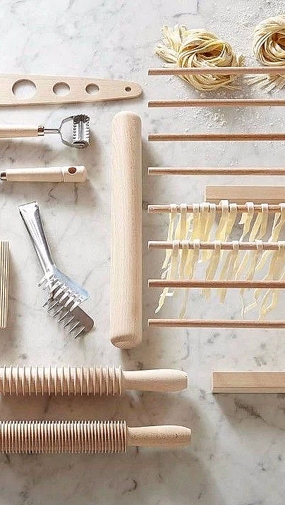 Pastaredskaper i tre på marmorbenk med tørkestativ, kjevler og fersk pasta