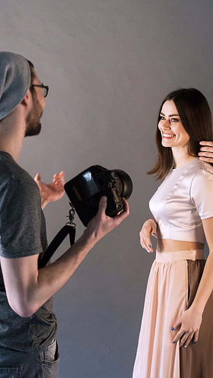 Fotograf og stylist som jobber med en smilende kvinne i et fotostudio