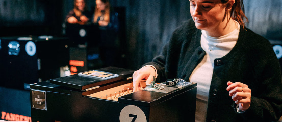 Kvinne ved en svart boks med tallet 7, ledninger og skiltet BE CREATIVE TEAM