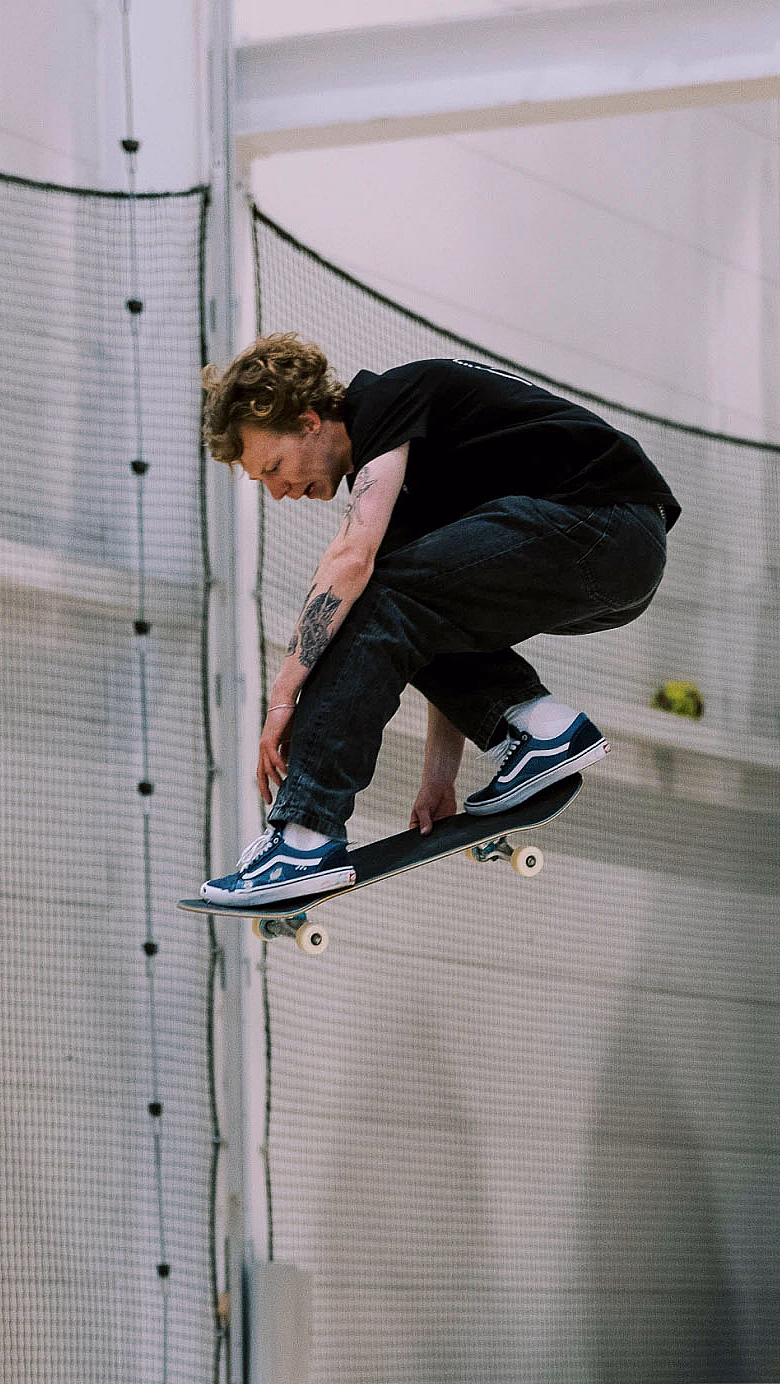 Person som gjør et hopp på skateboard i en innendørs sportshall