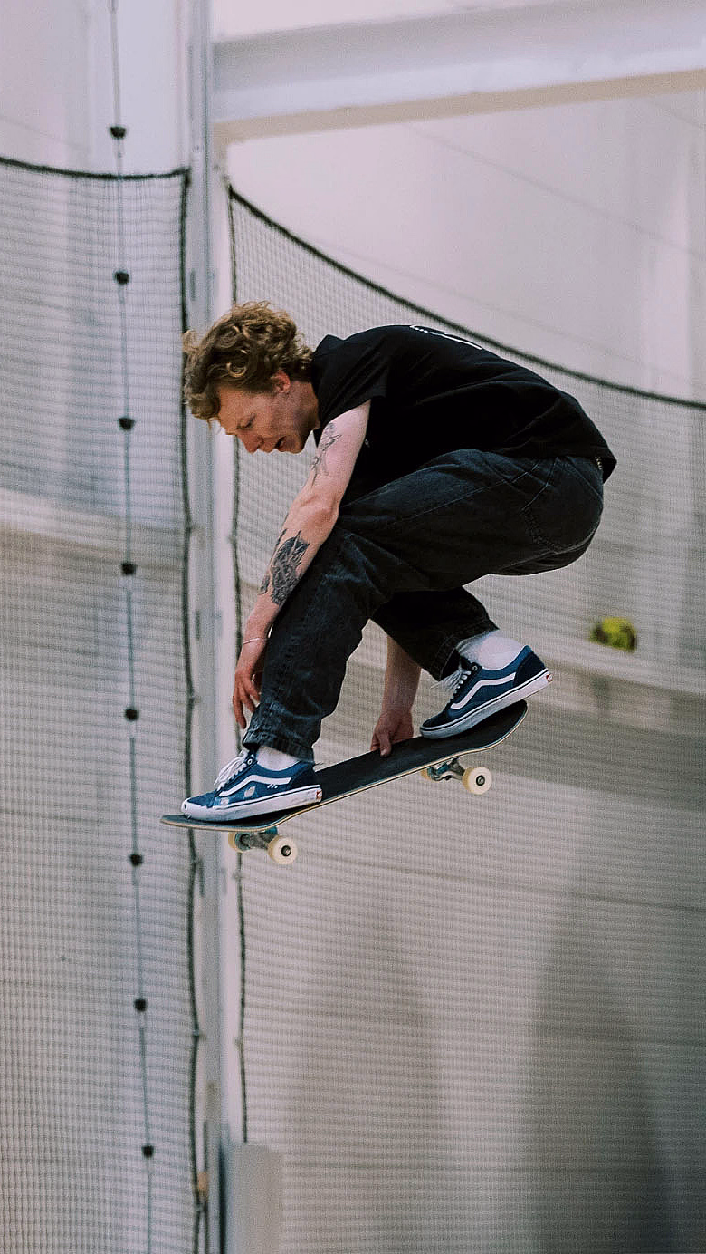 Person som gjør et hopp på skateboard i en innendørs sportshall