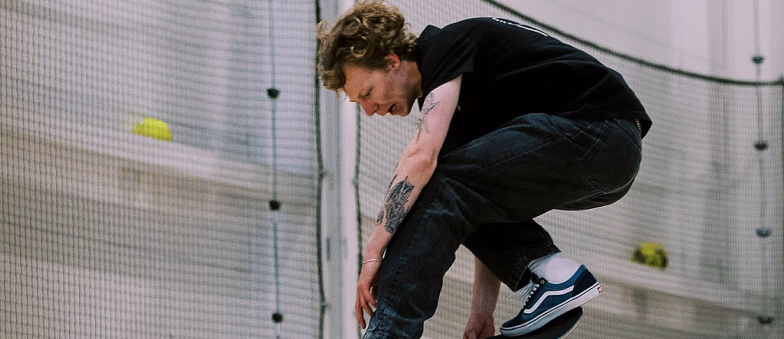 Person som gjør et hopp på skateboard i en innendørs sportshall