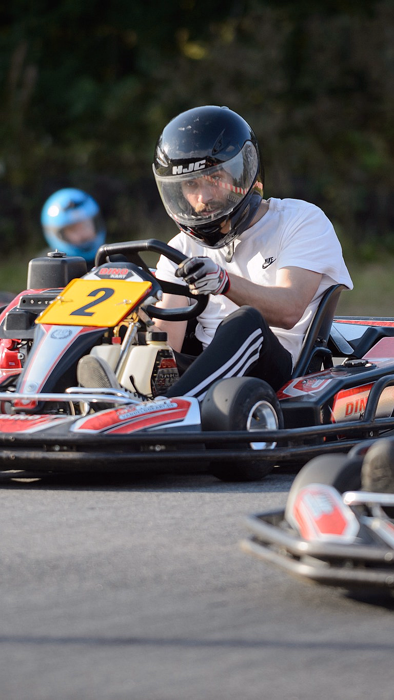 To personer kjører gokart på en utendørsbane