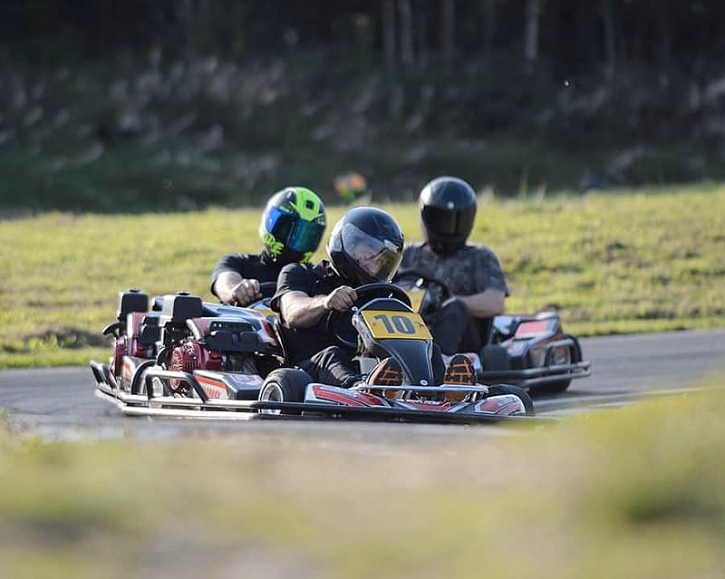 Tre personer kjører gokart på en bane med nummer 10 i front