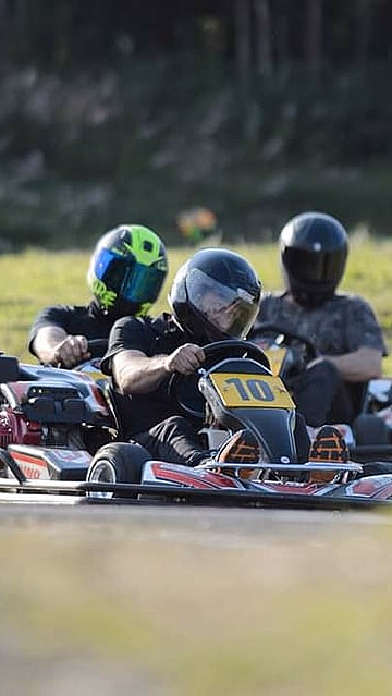Tre personer kjører gokart på en bane med nummer 10 i front