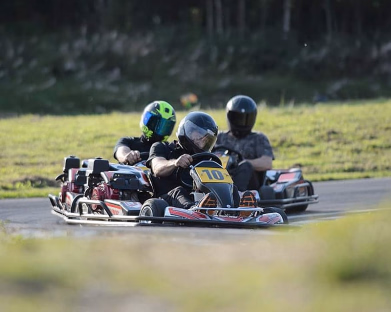 Tre personer kjører gokart på en bane med nummer 10 i front