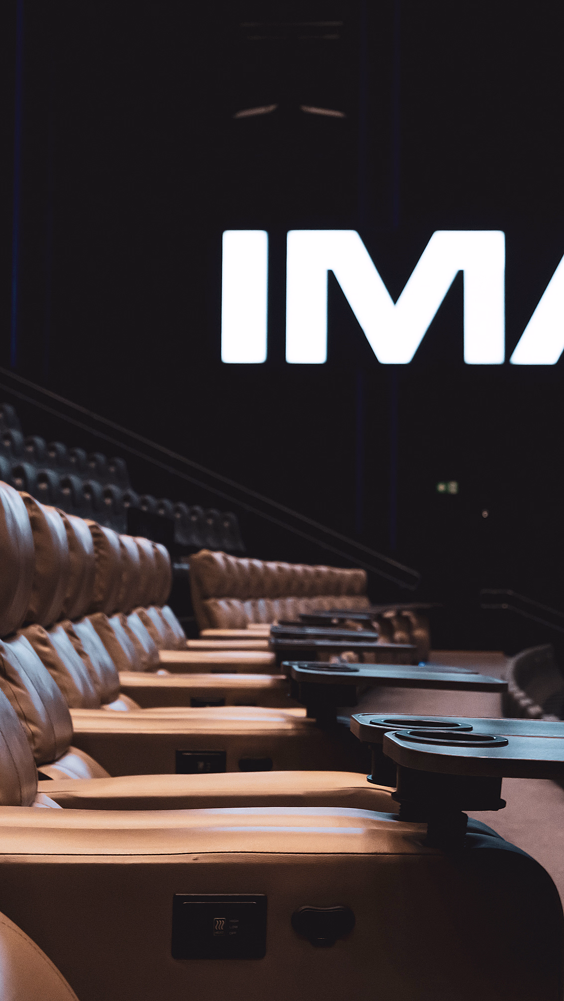 Kinosal med skinnseter og et stort lysende IMAX-skilt på veggen