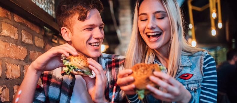 En mann og en kvinne som sitter sammen og spiser burgere på en restaurant
