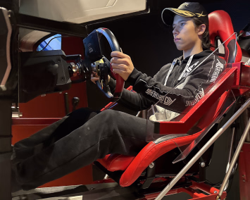 Person som sitter i en rød racingsimulator og holder i et ratt