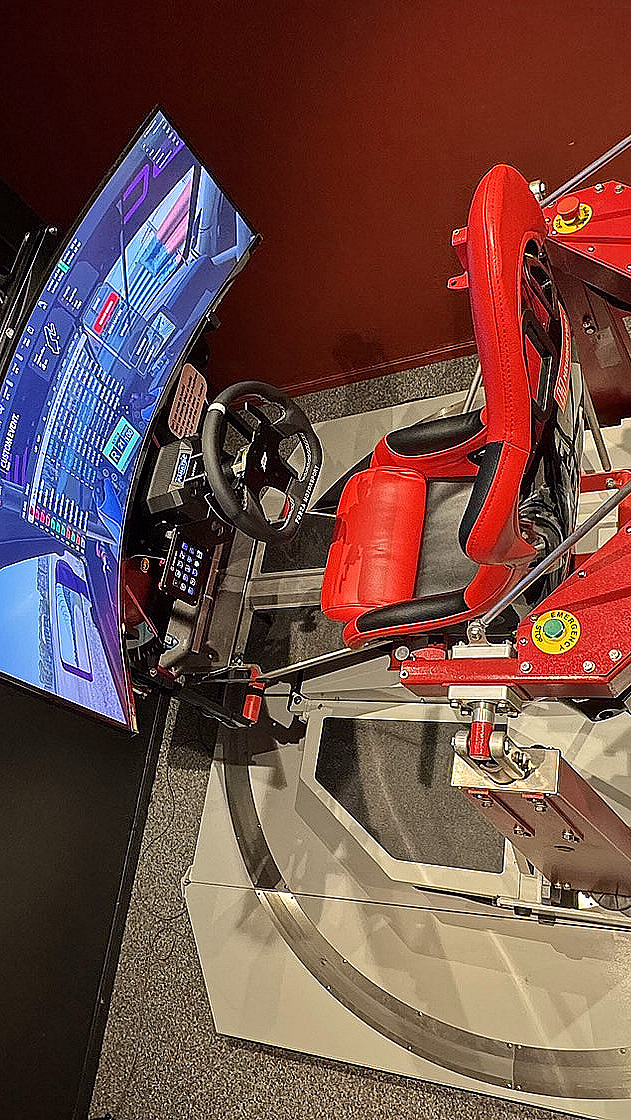 Avansert racingsimulator med rødt sportssete, ratt og en buet skjerm på en bevegelig plattform