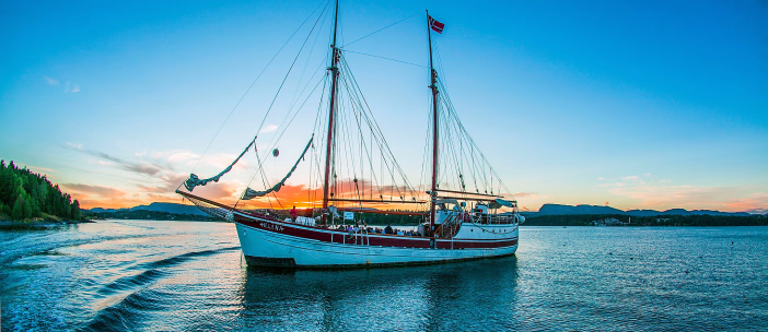 Seilskute med navnet Helena på vannet i solnedgang