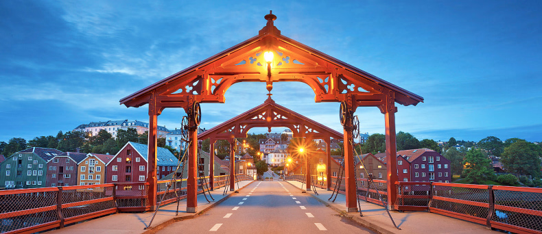 Gamle Bybro i Trondheim med fargerike bryggerekker i bakgrunnen ved skumring