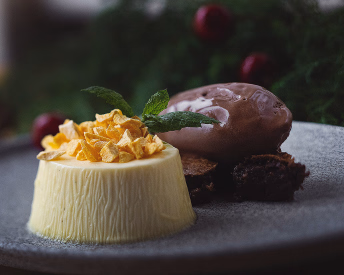 Pudding toppet med gule biter og en kule sjokolademousse på en tallerken
