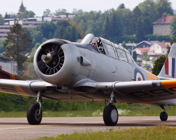 Et grått propellfly med gule vingetipper takser på en rullebane