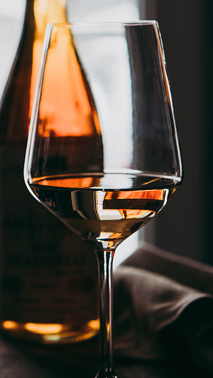 Tre glass med rød og hvit vin foran to flasker på et bord