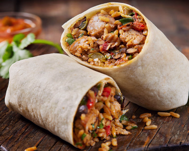 Halvert burrito på trefjøl fylt med ris, bønner, kjøtt og grønnsaker, med lime og rød saus