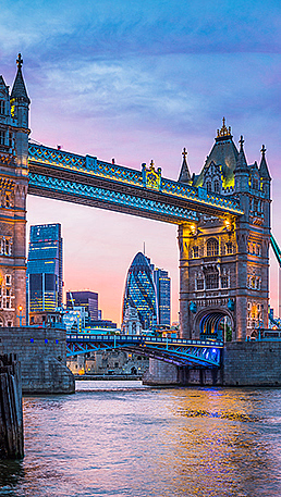 Tower Bridge opplyst ved solnedgang med bysilhuett i bakgrunnen
