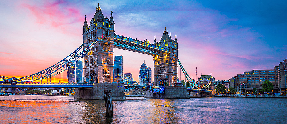 Tower Bridge opplyst ved solnedgang med bysilhuett i bakgrunnen