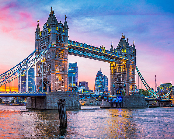 Tower Bridge opplyst ved solnedgang med moderne bygninger i bakgrunnen