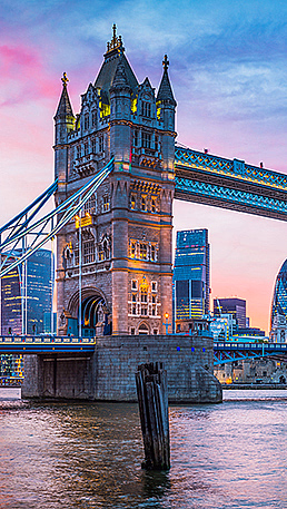 Tower Bridge opplyst ved solnedgang med moderne bygninger i bakgrunnen