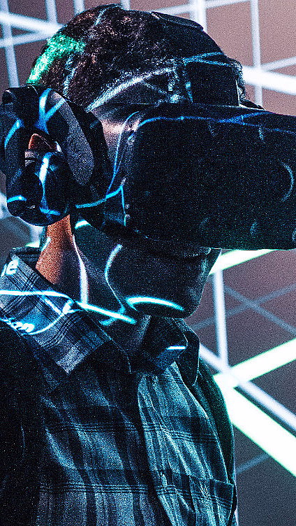 Person med VR-briller og hodetelefoner foran et digitalt rutenett