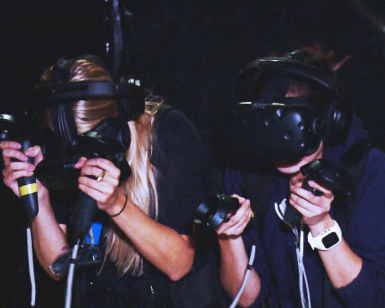 To personer med VR-briller og håndkontrollere i et mørkt rom