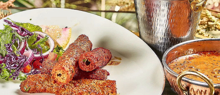 Grillede kjøttruller med salat på en tallerken, servert med ris og saus