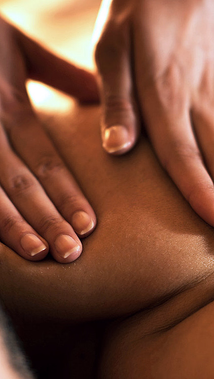 Nærbilde av hender som masserer skuldrene til en person som ligger på magen