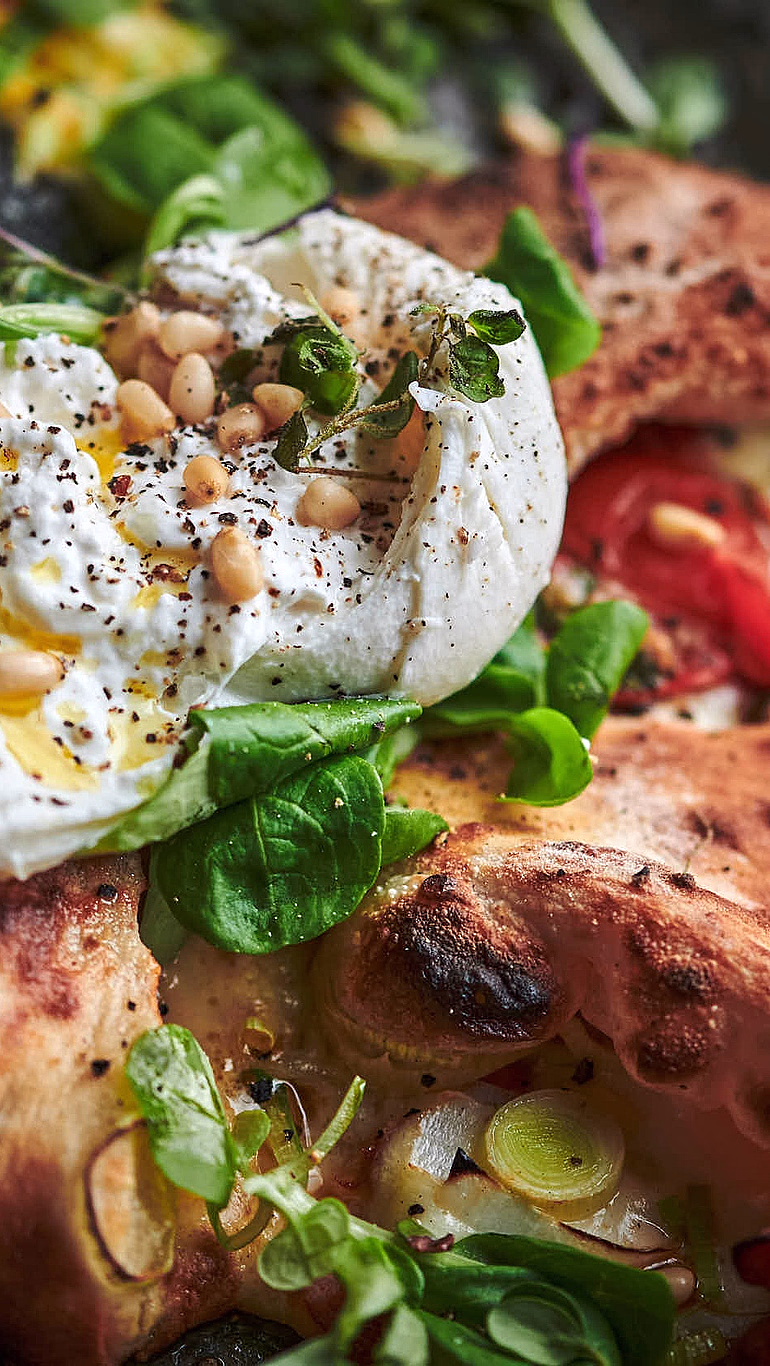 Pizza toppet med burrata, pinjekjerner og friske urter
