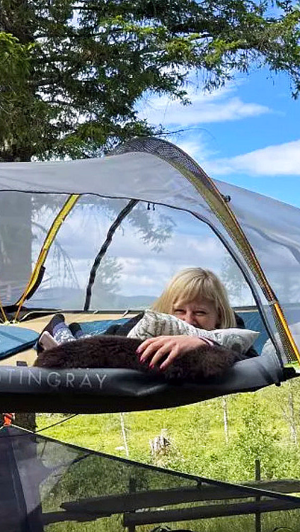 To personer som ligger i et svevetelt spent opp mellom trær i skogen