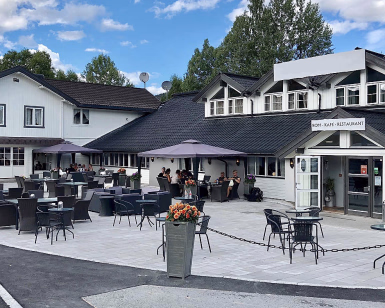 Uteservering ved en hvit trebygning med skiltet ROM - KAFÉ - RESTAURANT