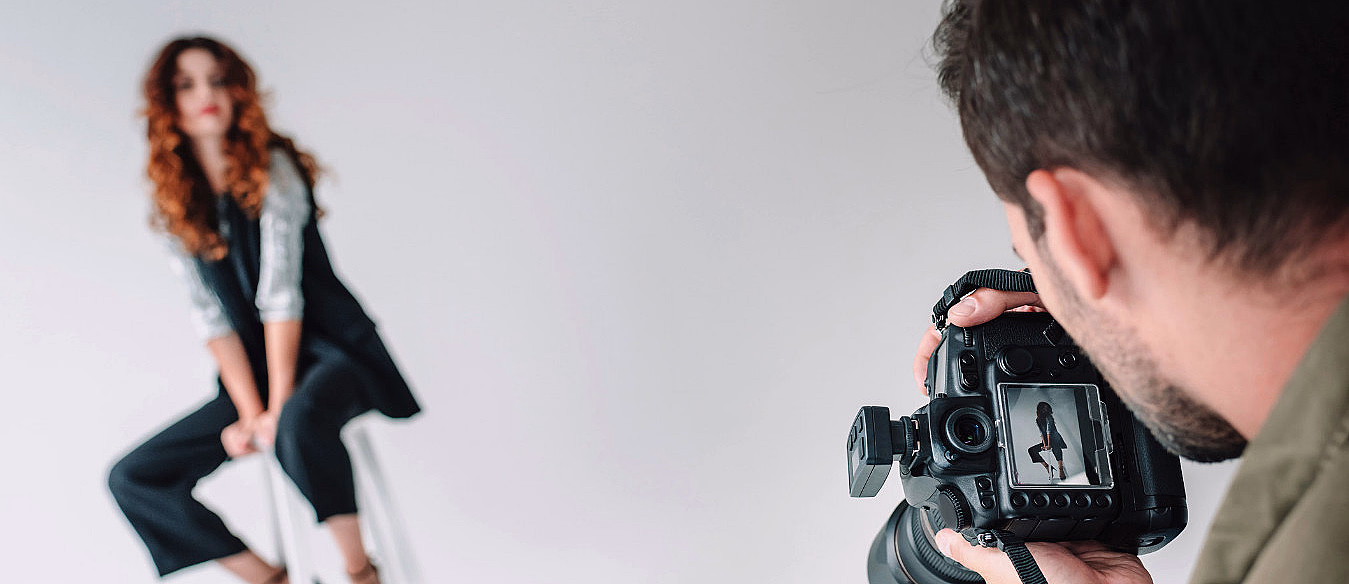 Fotograf som tar bilde av en kvinne i et fotostudio