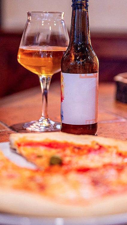 To personer som deler en pizza og drikker øl ved et bord