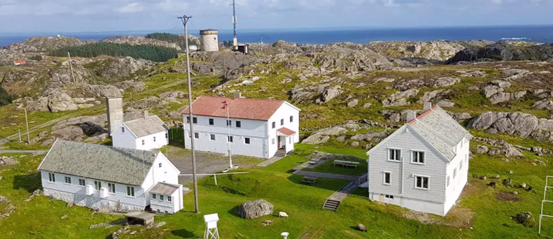 Hvite hus i et kupert kystlandskap med havet i bakgrunnen