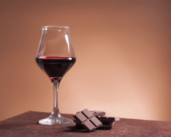 Et glass rødvin ved siden av biter med sjokolade