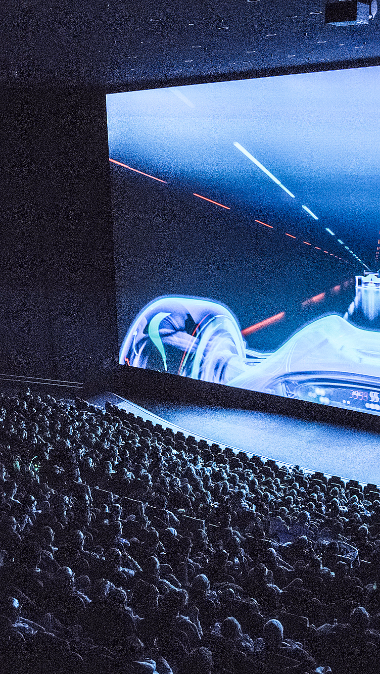 Publikum i en kinosal ser på en futuristisk racingscene på et IMAX-lerret