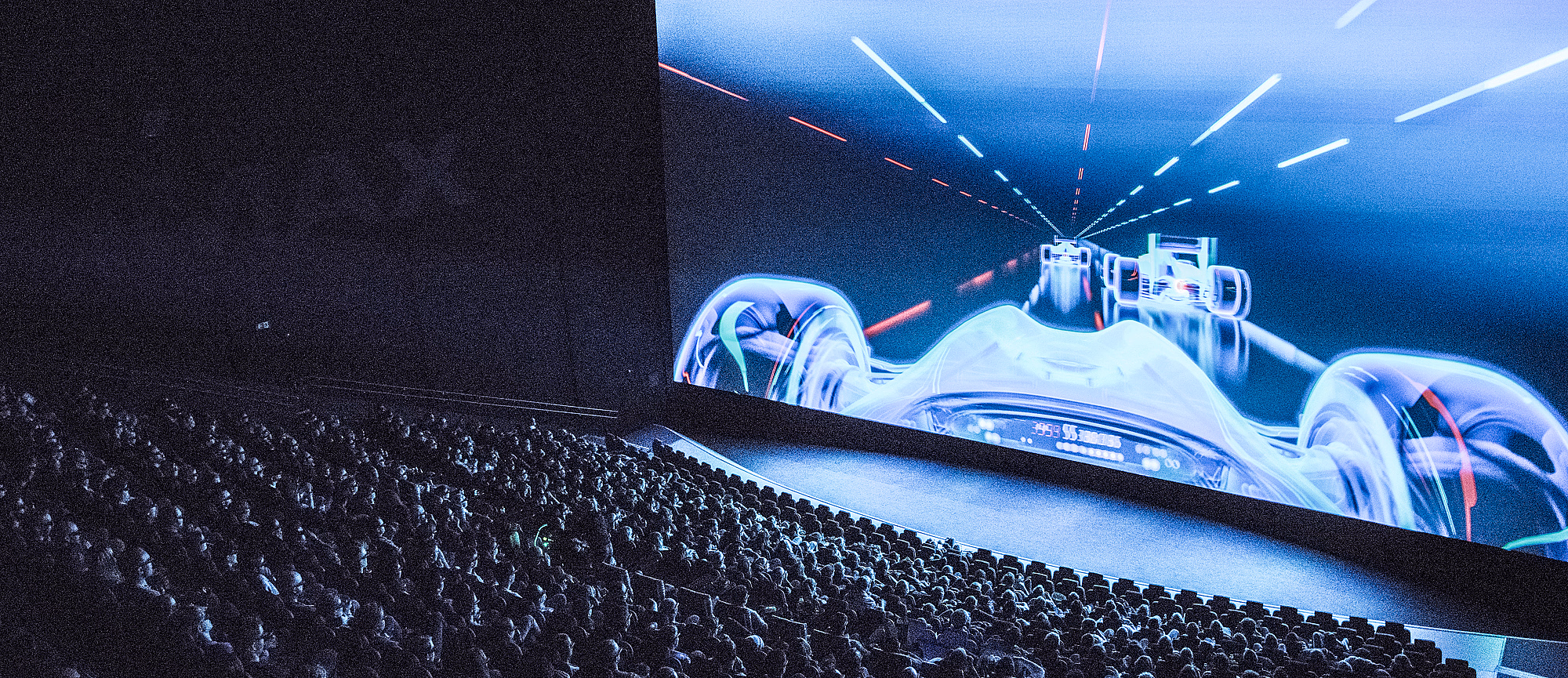 Publikum i en kinosal ser på en futuristisk racingscene på et IMAX-lerret