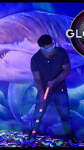 Person spiller minigolf i et neonbelyst rom med undervannstema og Glowing Golf-logo