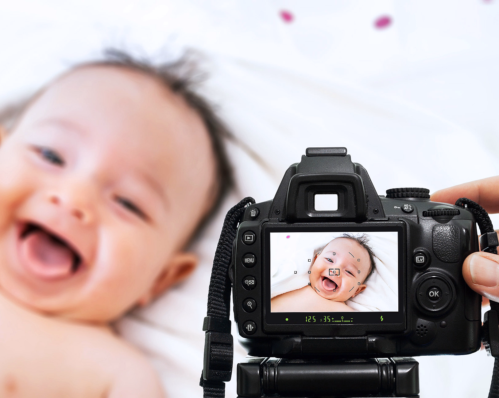 Hånd som holder et digitalkamera som viser en smilende baby på skjermen