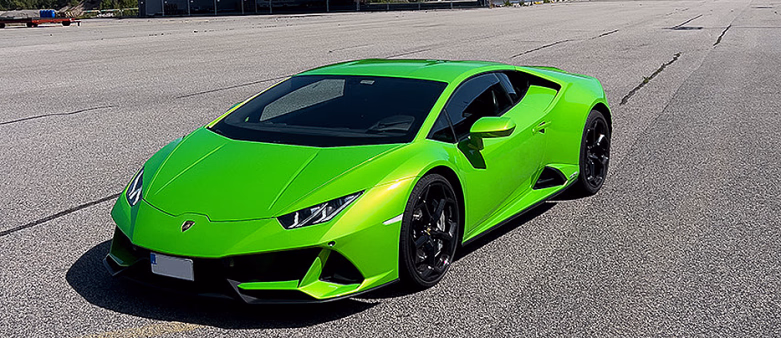 Grønn Lamborghini parkert på en asfaltert bane foran en stor grå hangar